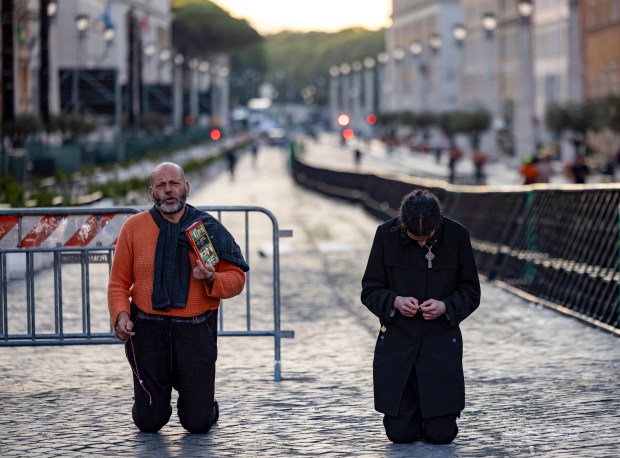 Two men recite prayers at sunrise in St. Peter's Square on May 16, 2025, days before the installation of Pope Leo XIV at the Vatican. (Brian Cassella/Chicago Tribune)