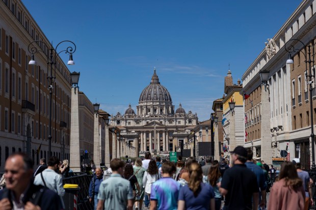 People walk down Via della Conciliazione near St. Peter’s Square...