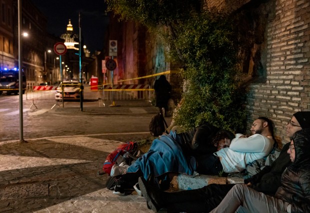 People sleep on the street before dawn while waiting to...