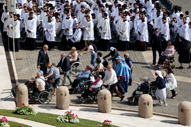 People in wheelchairs are moved to the front as Pope...