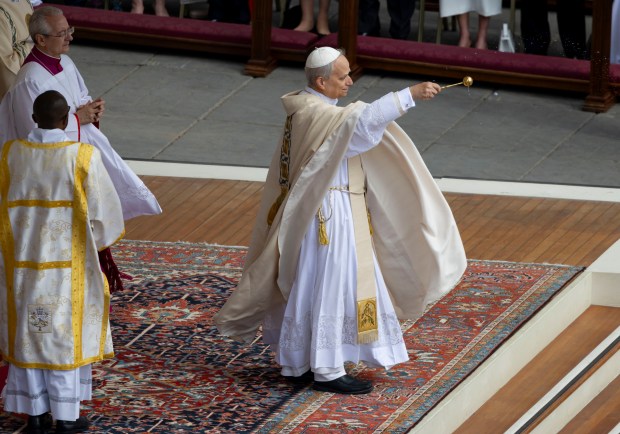 Pope Leo XIV sprinkles holy water during his installation Mass...