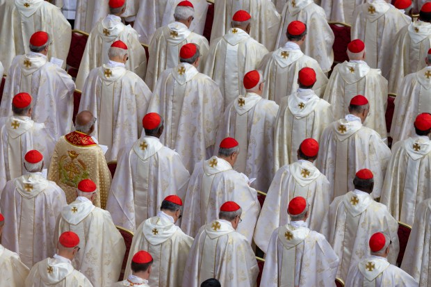 Members of the clergy pray as Pope Leo XIV is...