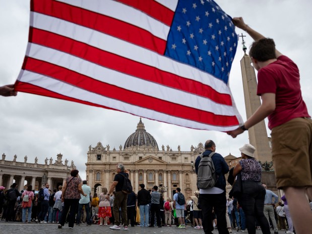 Two people hold an American flag while Pope Leo XIV holds his first general audience on May 21, 2025, in St. Peter's Square at the Vatican. (Brian Cassella/Chicago Tribune)