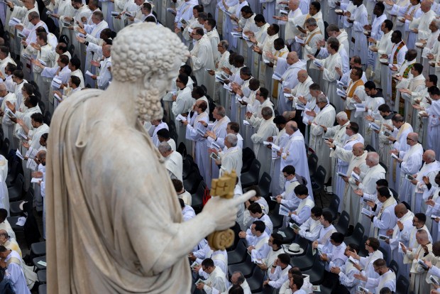 Members of the clergy pray as Pope Leo XIV is installed during Mass in St. Peter's Square on May 18, 2025, at the Vatican. (Brian Cassella/Chicago Tribune)
