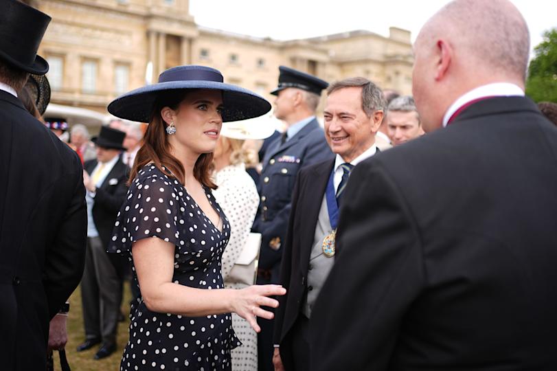 Princess Eugenie wearing a navy polka dot dress and blue hat at a garden party