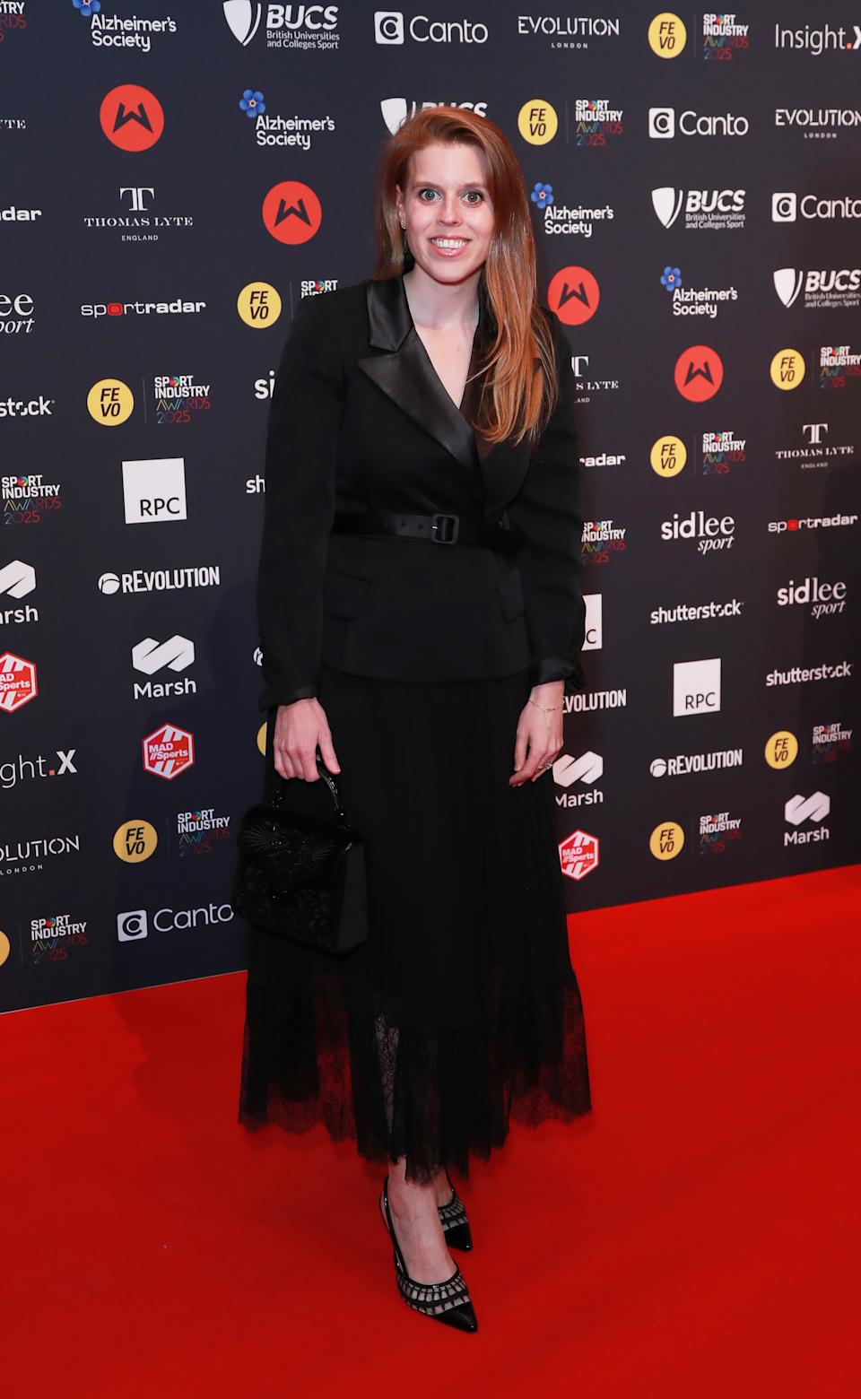 Princess Beatrice wearing a black blazer dress on a red carpet