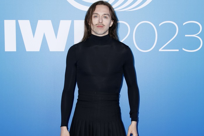 A person wearing a long sleeved black top and skirt, looking ahead.