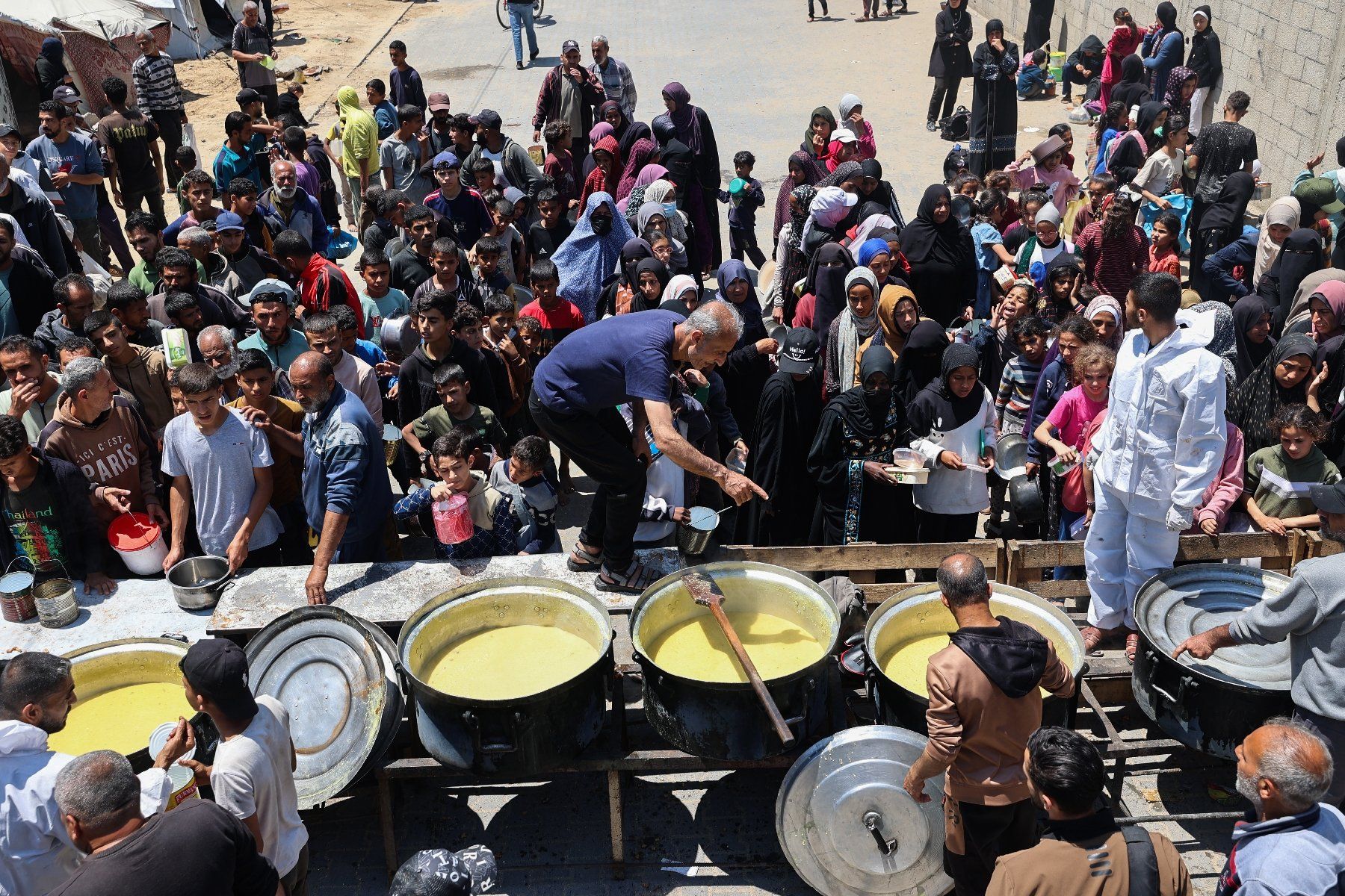 Des Palestiniens font la queue pour obtenir un repas chaud lors d'une distribution alimentaire au camp de réfugiés de Nousseirat, dans le centre de la bande de Gaza, le 4 mai 2025