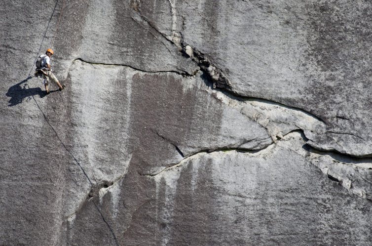 A person seen suspended from a rock face.