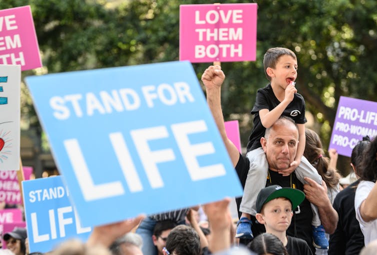Protest signs that say stand for life and love them both