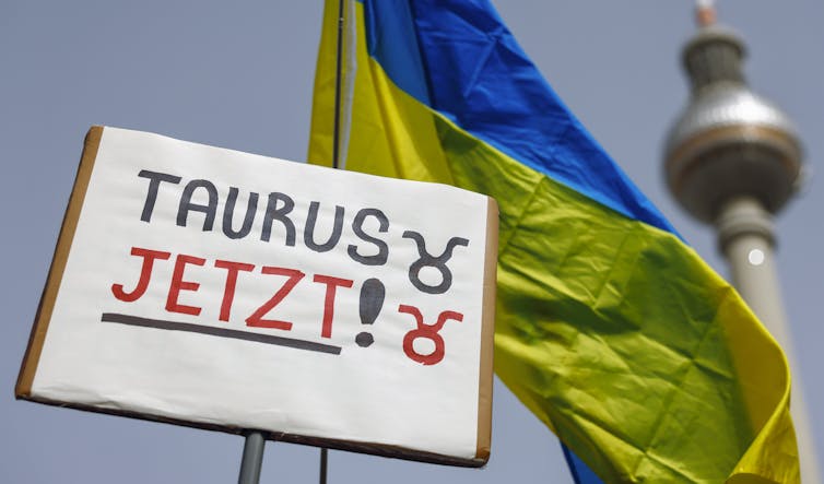 A places reasing Taurus now in German in front of a Ukrainian naitonal flag.