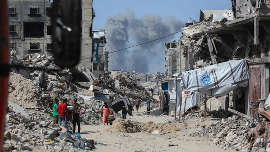 Smoke billows to the north as Palestinians move with their belongings through Jabalia while fleeing the northern Gaza Strip towards Gaza City on May 19, 2025. (AFP)