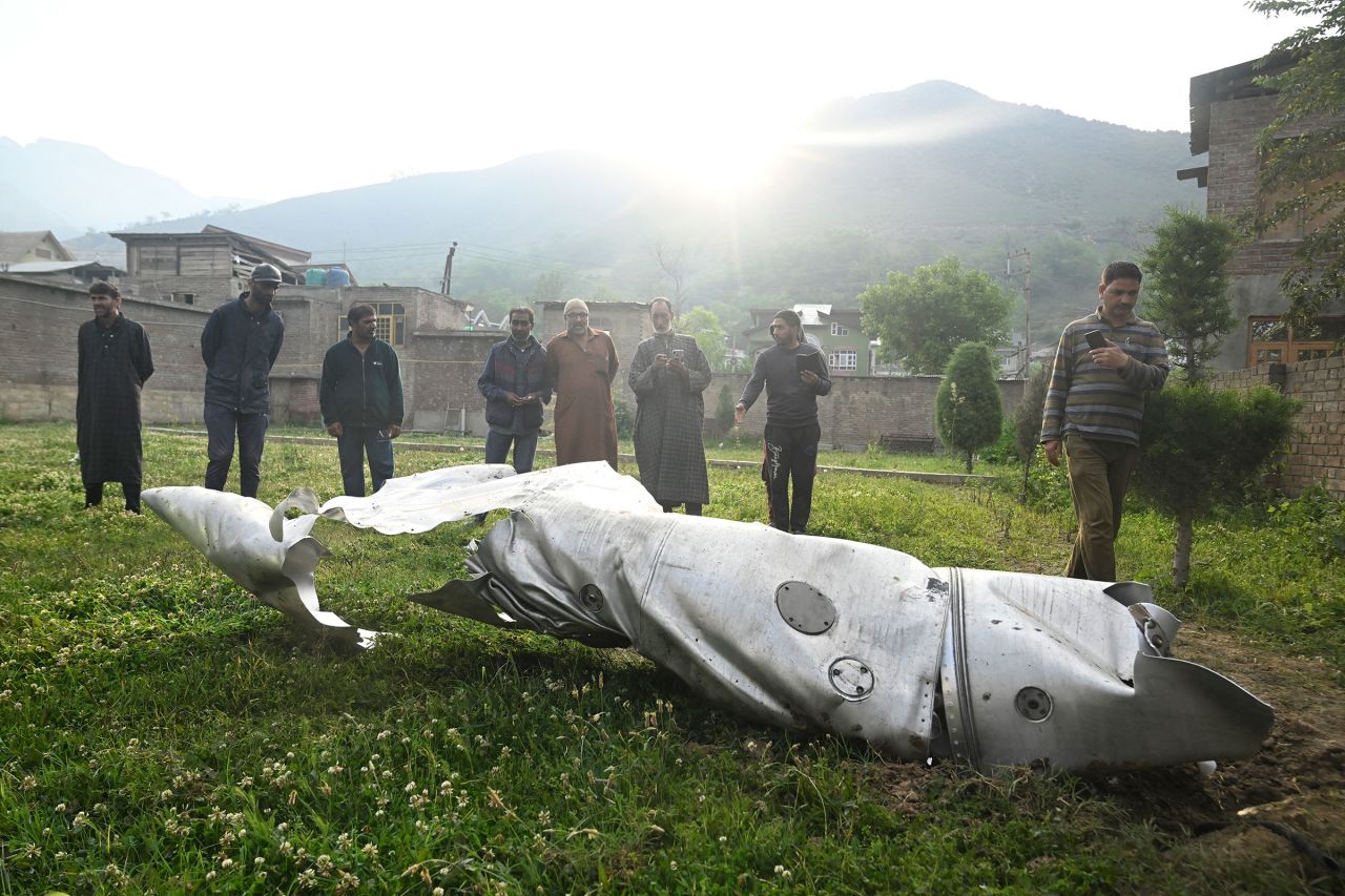 People look at the debris of an aircraft in Wuyan, India-administered Kashmir, on Wednesday. CNN cannot independently verify who the aircraft belonged to or what brought it down.