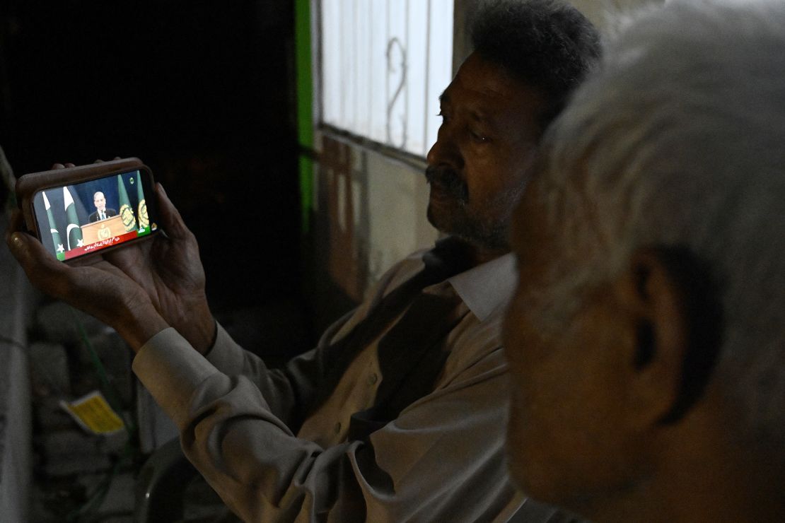 Residents watch a smartphone as Pakistan's Prime Minister Shehbaz Sharif addresses the nation in Islamabad on May 10, 2025.