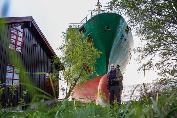 Johan Helberg poses next to his house and a 443-foot-long container ship by the shore in the Trondheimsfjord outside Byneset by Trondheim, Norway, on May 22, 2025, after the ship ran aground, almost hitting his house. 