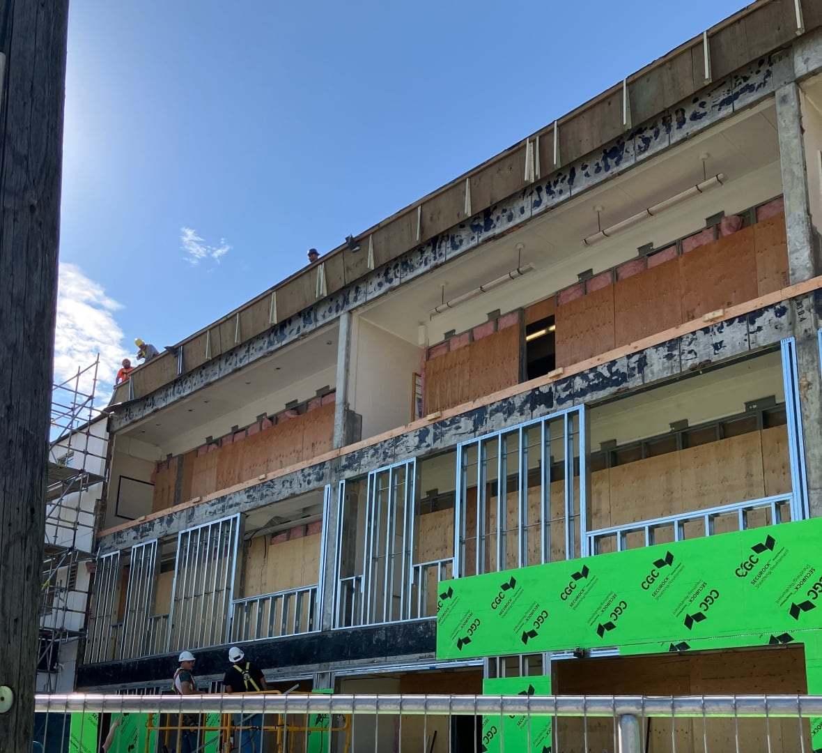 The face of a building that's under construction. A fence is put up in front of the building.
