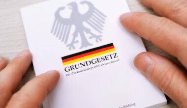Zwei Hände streichen über die Ränder eines deutschen Grundgesetzes.