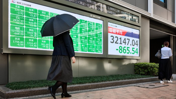 A person holding up an umbrella is walking past the screen