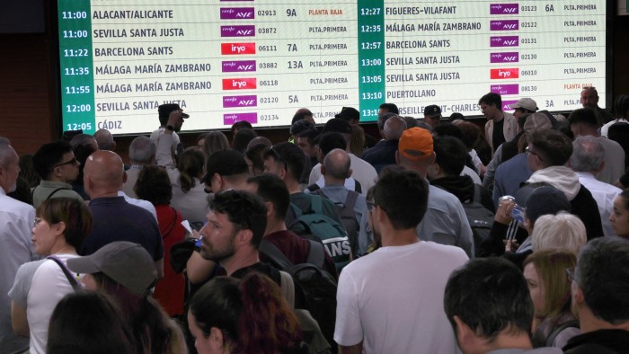 Passengers wait in front of a train services information board at Atocha station in Madrid