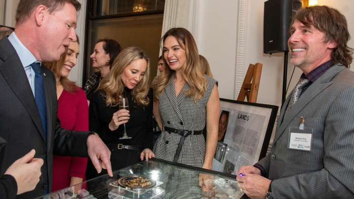 Attendees interacting and viewing displayed jewelry pieces at a sophisticated indoor event