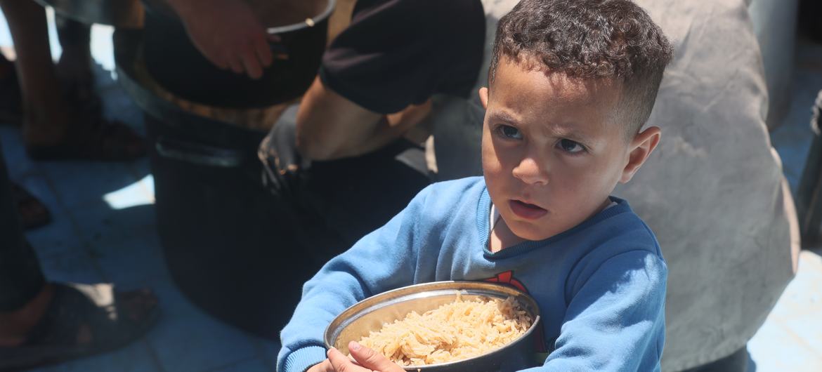 Un niño de Gaza lleva un plato con arroz.