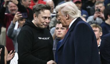 Elon Musk og Donald Trump tar hverandre i hendene og ser på hverandre.