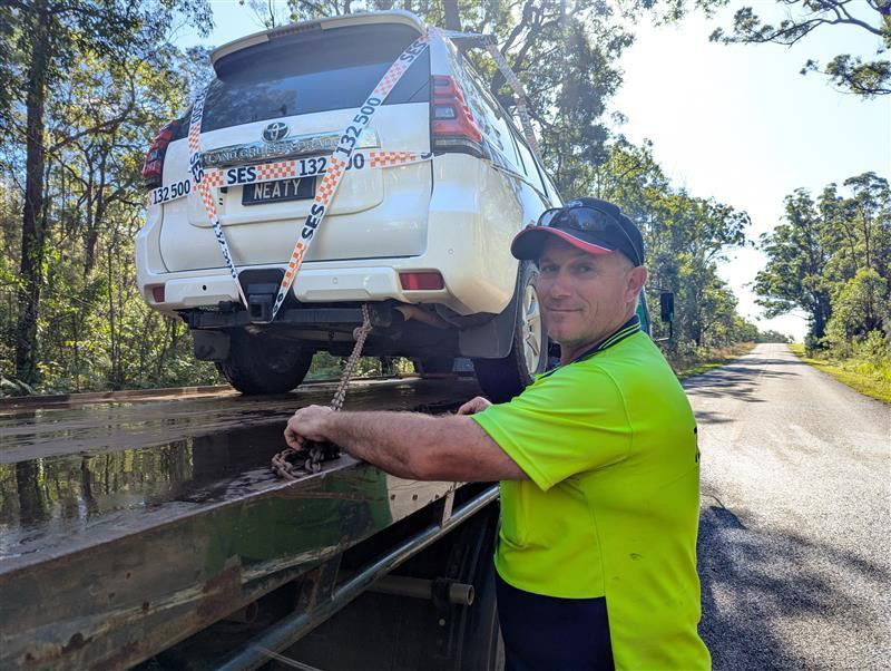 A tow truck driver puts a car on the back of his tow truck