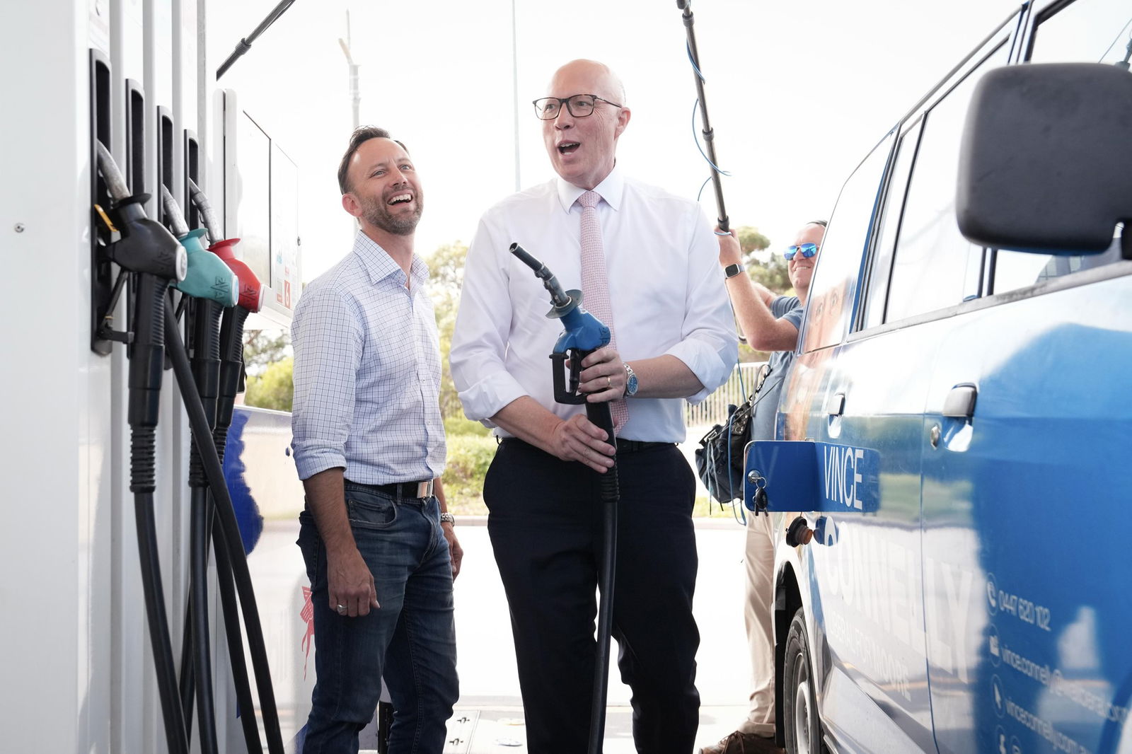 Peter Dutton laughs at a petrol pump.