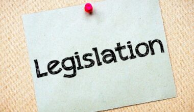 Sticky note attached to a wall with a red push pin that says 'legislation'