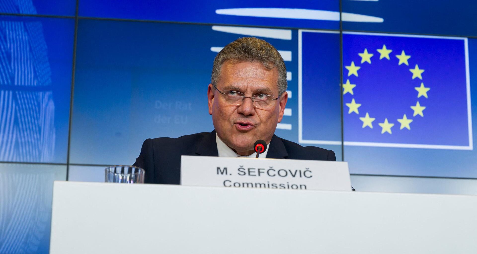 Kommissar für Handel und Wirtschaftliche Sicherheit, Sefcovic, sitzt hinter einem Rednerpult. Vor ihm steht sein Namensschild, hinter ihm an der Wand das Logo der EU.