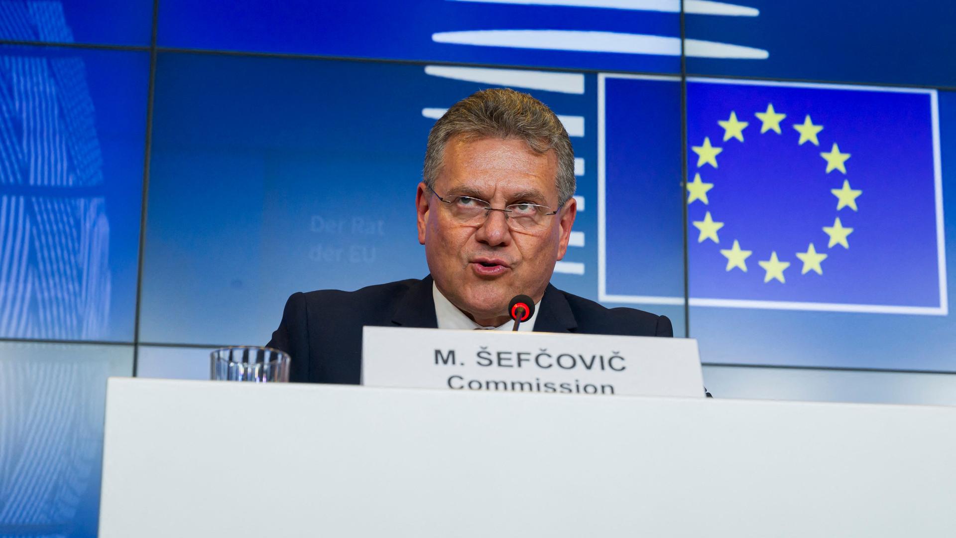 Kommissar für Handel und Wirtschaftliche Sicherheit, Sefcovic, sitzt hinter einem Rednerpult. Vor ihm steht sein Namensschild, hinter ihm an der Wand das Logo der EU.