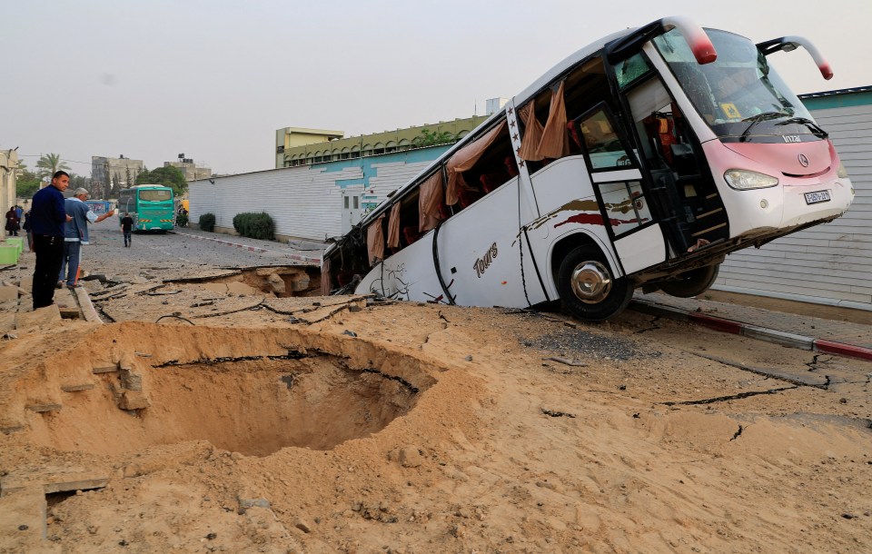 Bus in a large hole in the road after airstrikes.