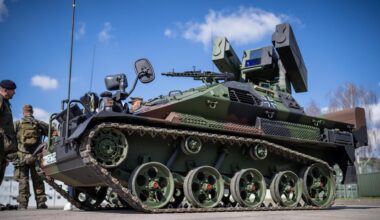 Ein Panzer mit Raketen. Bei dem Panzer stehen mehere Männer. Sie tragen Militär-Anzüge.
