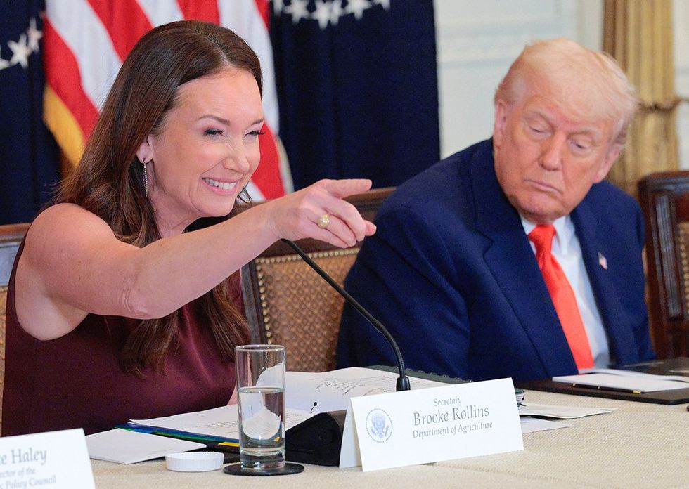 \u200bAgriculture Secretary Brooke Rollins points and smiles while president donald trump looks downward toward her