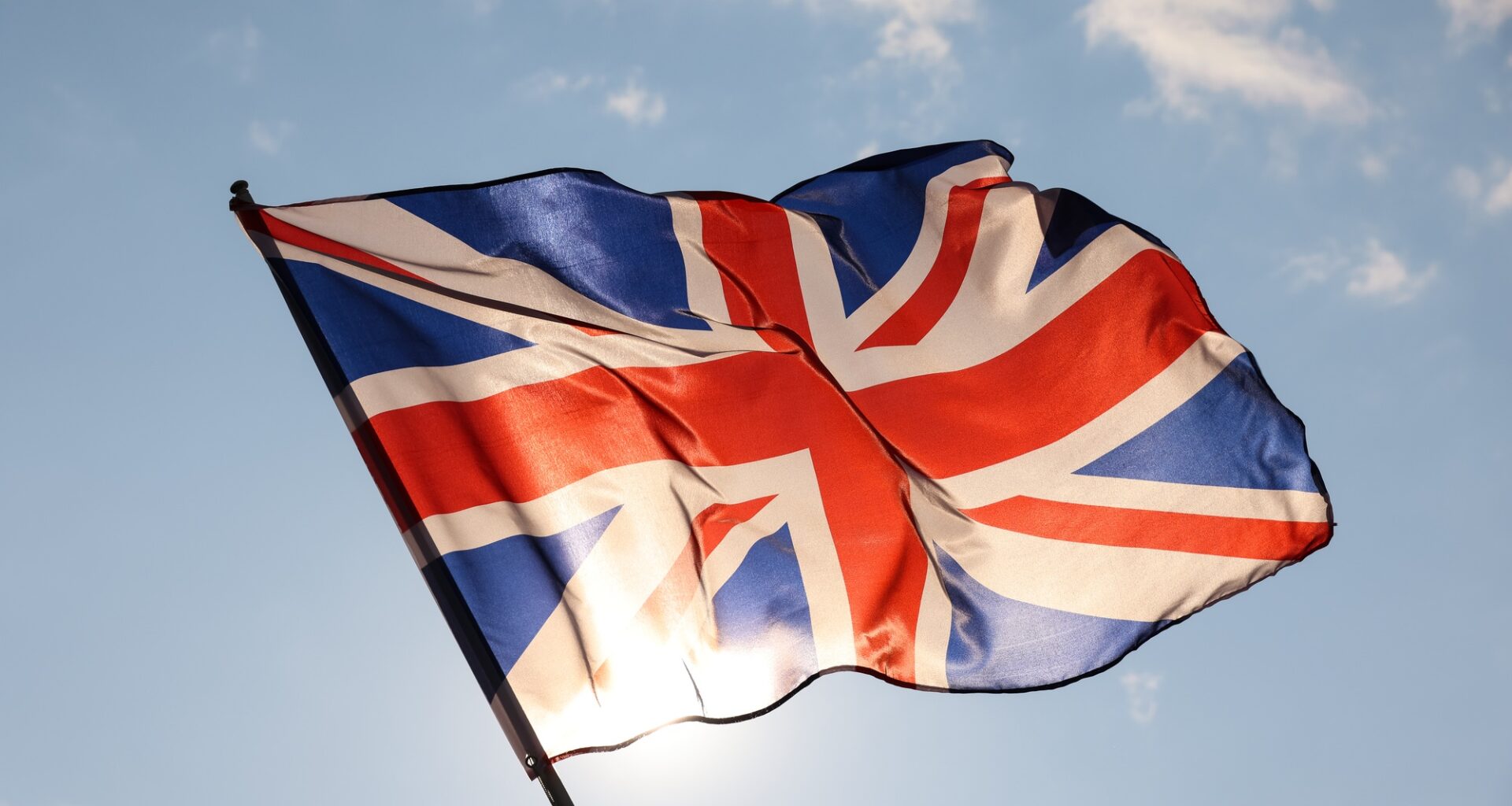 UK Great Britain flag waving in cloudy blue sky