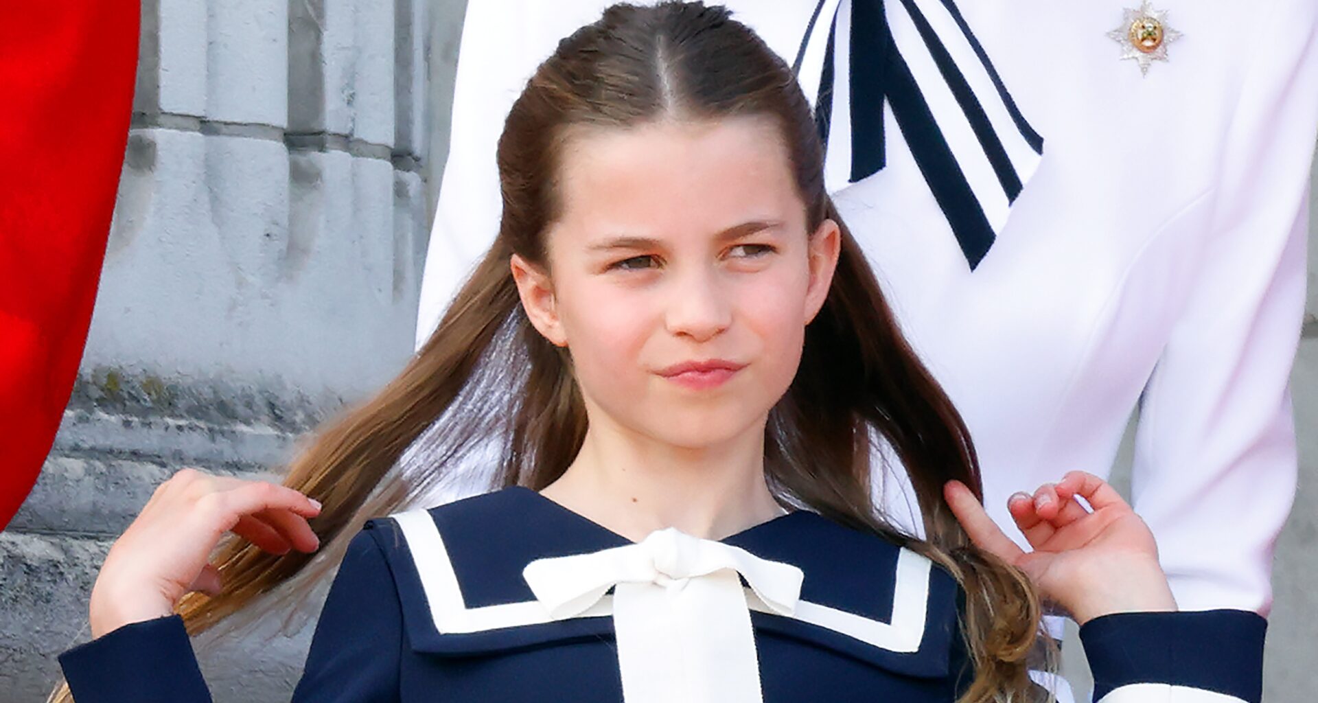 Princess Charlotte flips back her hair as she watches an RAF flypast from the balcony of Buckingham Palace after attending Trooping the Colour on June 15, 2024