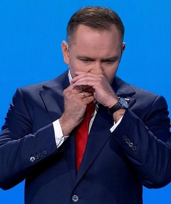 Man in suit using hands to cover his mouth and nose.