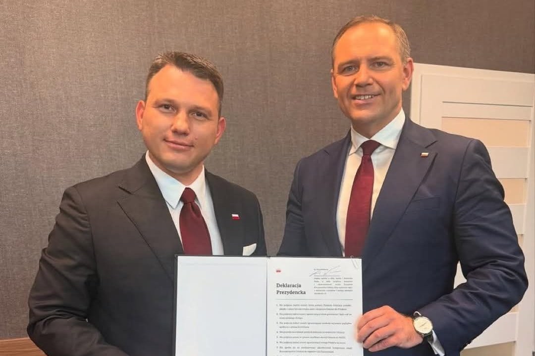 Two men in suits signing a document.