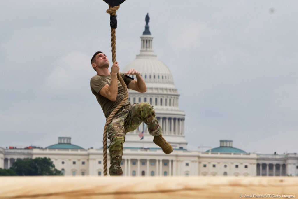 Un soldado trepa una cuerda durante una competencia de acondicionamiento físico, con el Capitolio de Estados Unidos al fondo (© Amid Farahi/AFP/Getty Images)