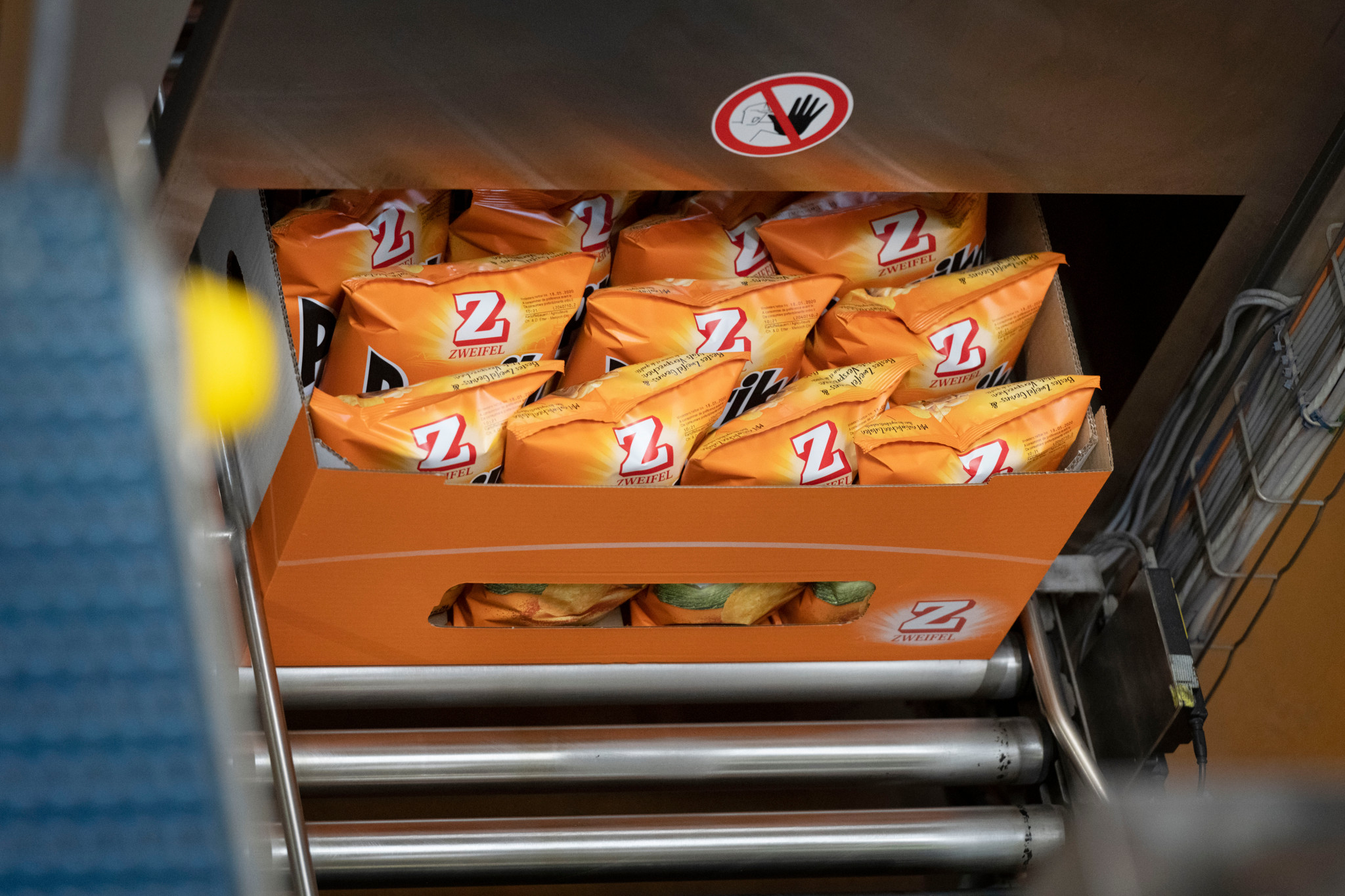 Production de chips Zweifel Pomy à Spreitenbach, montrant des paquets de chips orange dans une boîte.