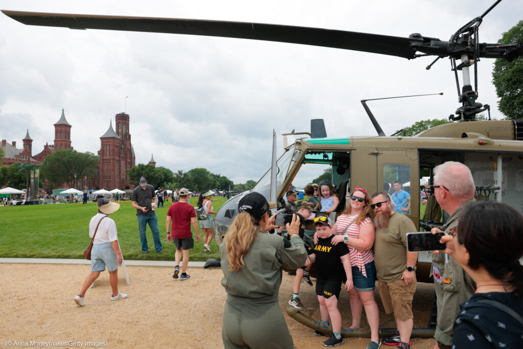 Asistentes posan para una foto con un helicóptero en el Paseo Nacional (© Anna Moneymaker/Getty Images)