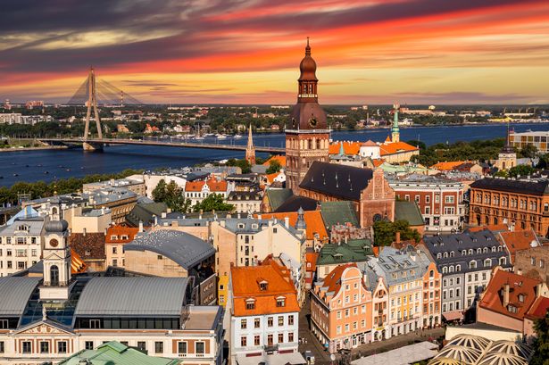 Riga, Latvia: aerial panoramic top view of Old Town and Daugava River at sunset. The tower of Dome Cathedral, a symbol of the Latvian capital city.