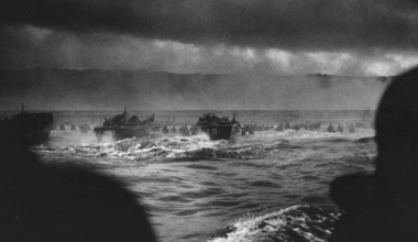 LCVP Higgins Boats approach the sands of Omaha Beach, where men can be seen wading ashore under German fire. June 6, 1944.