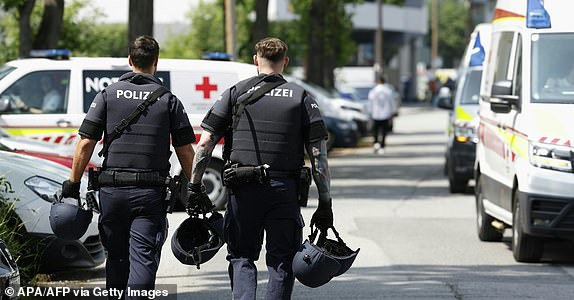 Two policemen walk past ambulance cars in a street close to a school where, according to reports, several people died in a shooting, on June 10, 2025 in Graz, southeastern Austria. Several people died in a school shooting, including the attacker, Austrian broadcaster ORF quoted the interior ministry as saying. (Photo by ERWIN SCHERIAU / APA / AFP) / Austria OUT (Photo by ERWIN SCHERIAU/APA/AFP via Getty Images)