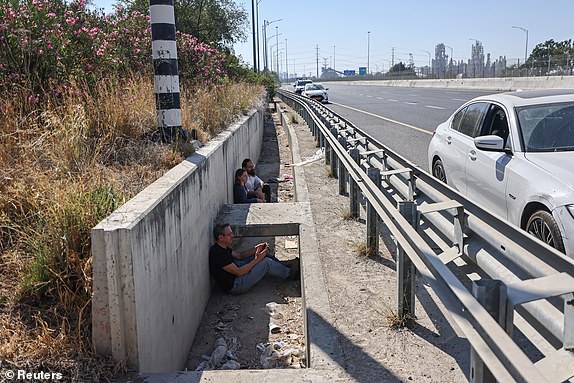 Israelis take shelter at the side of a highway as siren sounds following missile attack from Iran on Israel, Near Shaar HaGai, Israel June 15, 2025. REUTERS/Jamal Awad