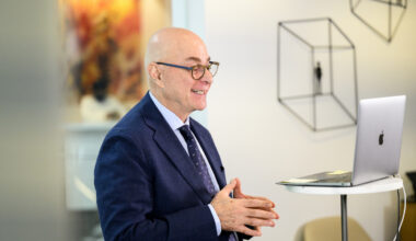 Northeastern President Joseph E. Aoun speaks during a virtual conference, smiling while standing in front of a laptop.