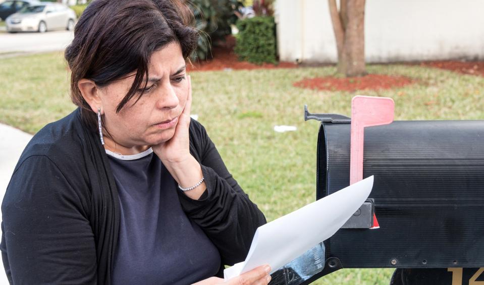 Woman at mail box receiving bad news.