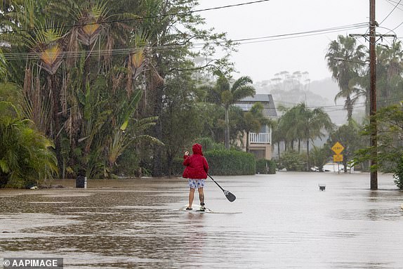 A person uses a paddleboard on a flooded street in Maitland, New South Wales, Friday, May 23, 2025. (AAP Image/Renee Moore) NO ARCHIVING 14858951
