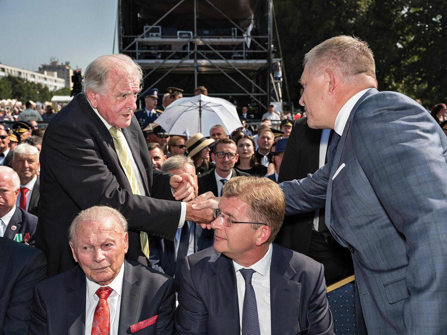 29. august 2024, Banská Bystrica: Premiér Robert Fico si podáva ruku s bývalým premiérom Vladimírom Mečiarom na oslavách 80. výročia SNP. V popredí bývalý prezident Rudolf Schuster.