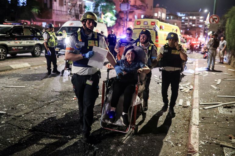 A wounded woman is taken on a stretcher after missiles fired at Tel Aviv